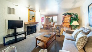 Een woonkamer met een televisie, open haard, bank en salontafel.