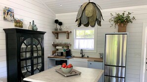 Una cocina con una mesa de madera, armarios negros, un refrigerador de acero inoxidable y una lámpara colgante con forma de hoja.