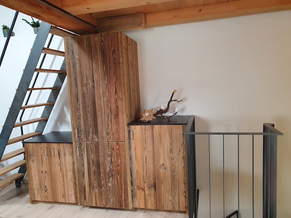 Un meuble en bois avec une échelle, une branche ornée d’oiseaux décoratifs et une rambarde en métal.