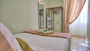 A bedroom with a bed, a mirror, a wardrobe, and a window with curtains. - Anesis Studio Old Corfu Town (Corfu)