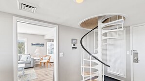 Un salon moderne avec un escalier en colimaçon, un canapé, une table basse et un coin repas.