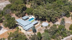 Vue aérienne d’une propriété comprenant un grand bâtiment, une piscine et un réservoir d’eau.