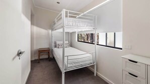 Une chambre avec un lit superposé, une petite table et un bureau.