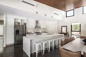 A modern kitchen with a central island, bar stools, and a dining area with a large table.