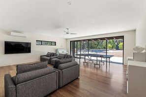 A modern living room with a sectional sofa, a flat-screen TV, and a dining area with a table and chairs.