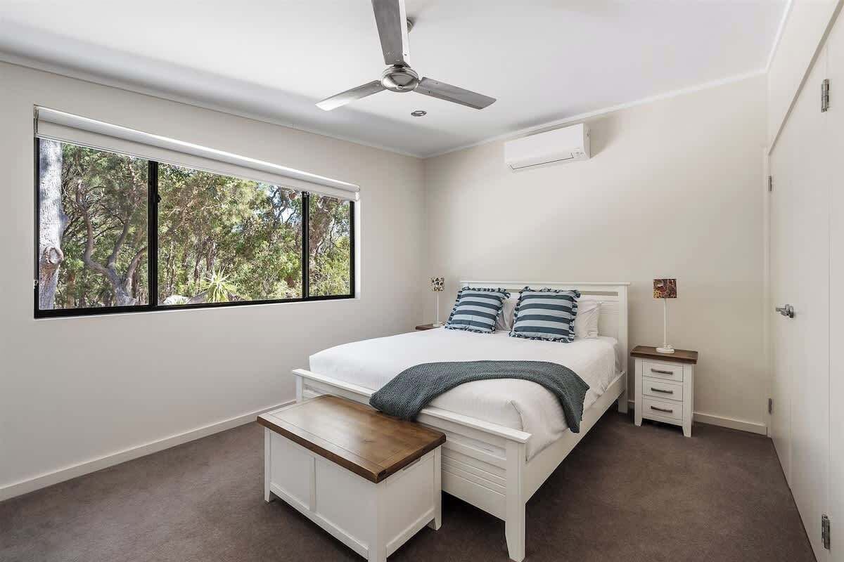 Une chambre à coucher comprenant un lit, une table de chevet, une commode et un ventilateur de plafond.