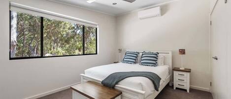 Une chambre à coucher comprenant un lit, une table de chevet, une commode et un ventilateur de plafond.