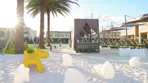 A beach area with a yellow sculpture, white ice sculptures, palm trees, and a covered seating area with umbrellas. - Near Disney/3BDR/Entire Home/Free Use of property Amenities/Wi-Fi/Parking (Kissimmee)