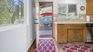 A kitchen with wooden cabinets, a stainless steel dishwasher, and a window with blinds.