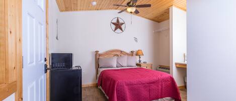 A bedroom with two beds, a ceiling fan, a star decoration, a desk, and a refrigerator.