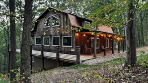 A rustic cabin with a wooden exterior, large windows, and a deck. - Beautiful Cabin on 20 Acres in Hocking Hills Ohio - Early Bird Discounts! (Rockbridge)