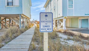 Placa indicando acesso à praia para uma casa de temporada a oeste.