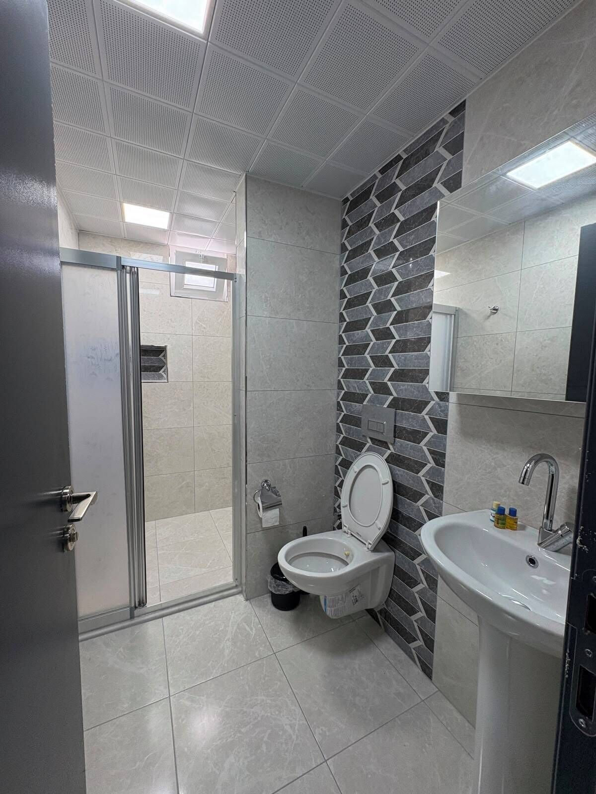 A modern bathroom with a shower, toilet, and sink.