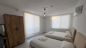 Un dormitorio con dos camas, un armario de madera y una lámpara en el techo.