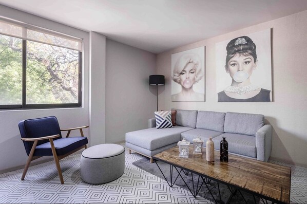 Relax in this stylish living room with a light grey sofa, dark blue armchair, and geometric patterned rug.