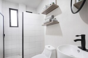 Bathroom features a shower area with a glass door, a toilet, and a sink with a black faucet.