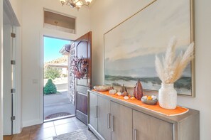 Stunning hallway with a large painting, pampas grass, and decorative accents leads to a beautiful outdoor view.