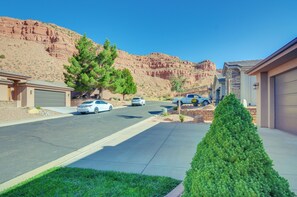 Stroll through a serene suburban neighborhood surrounded by natural red rock formations and lush greenery.