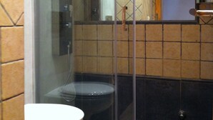 Un baño con ducha envuelta en cristal, un inodoro y un lavamanos.