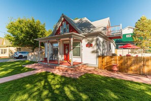 A two-story house with a red and white exterior, a front porch, and a visible address sign. - Ladybug I: Bikes & Fire Pit Fun (Fruita)