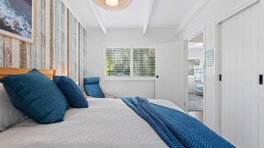 Un dormitorio con cama, una silla, una ventana y un armario.