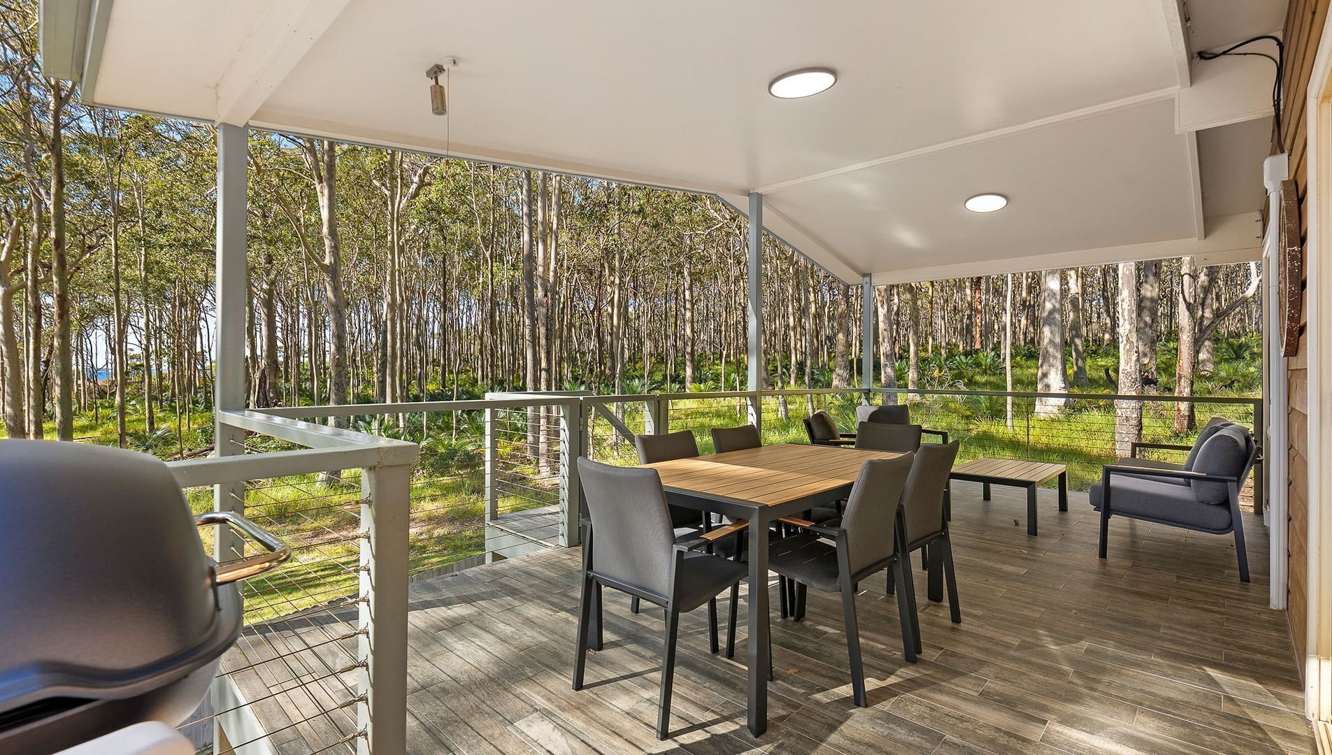 Un espace extérieur abrité où l’on peut prendre ses repas, avec vue sur une forêt.