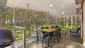 Un área de comedor al aire libre techada, con vista a un bosque.