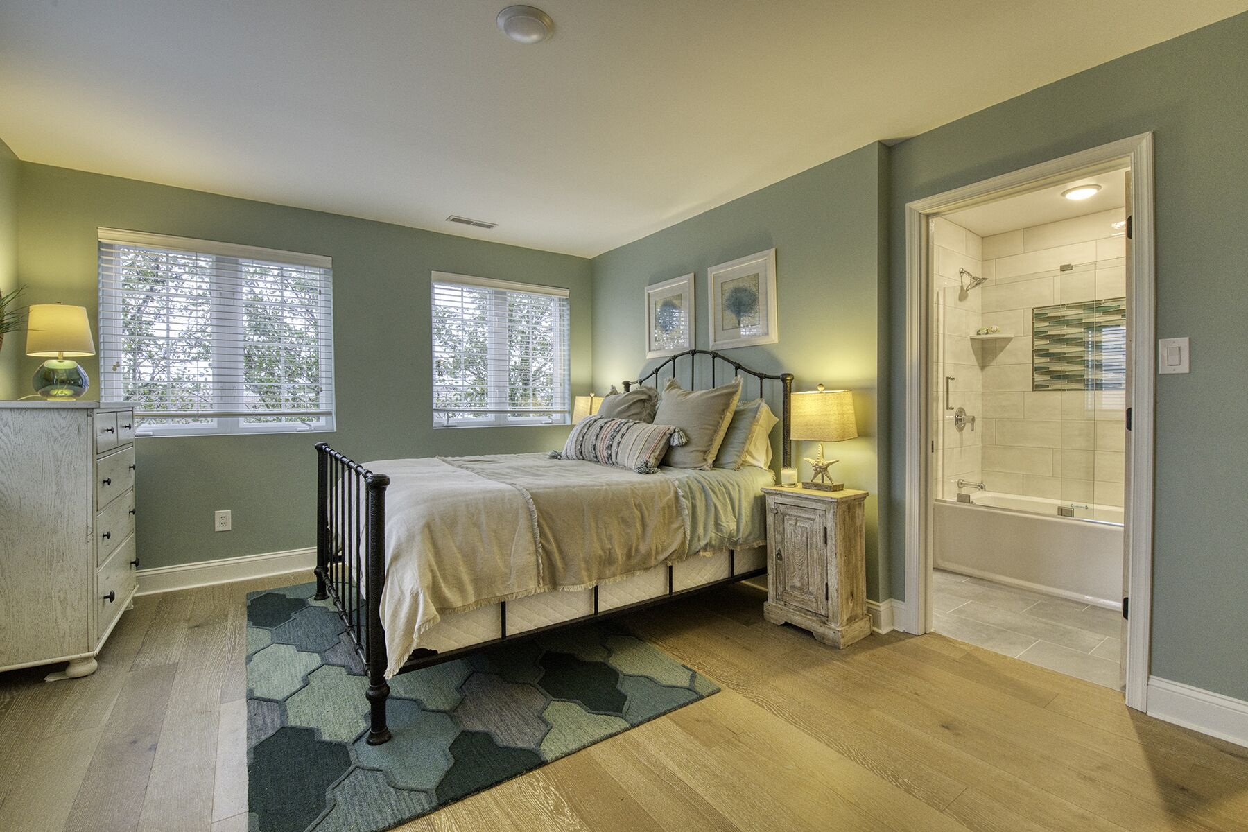 A bedroom with a bed, bedside tables, a dresser, and a walk-in closet.