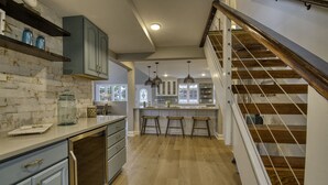 Une cuisine avec un mur recouvert de briques, un plancher en bois et un escalier doté d’une rampe.