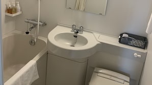 A modern bathroom with a bathtub, sink, toilet, and a mirror with a light.