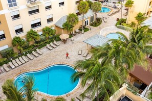 A hotel with multiple swimming pools, lounge areas, and palm trees.