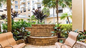 Une cour avec un foyer en pierre, deux fauteuils en osier et une végétation tropicale luxuriante.