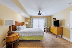 Ein Hotelzimmer mit Bett, Fernseher, Schreibtisch und Deckenventilator.