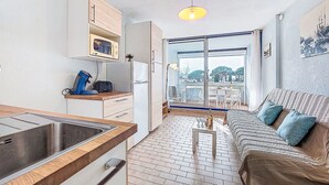 Een compact woongedeelte met een kitchenette, een eethoek en een bank.
