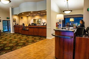 Welcome to our hotel lobby, featuring a reception desk, comfortable seating area, and a large mirror.