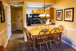 Enjoy meals in this cozy dining area with a table and chairs, adjacent to a modern kitchen and a door leading to another space.