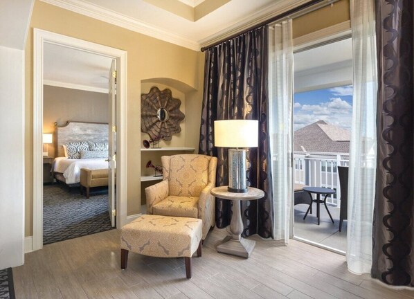 A hotel room with a bed, a chair, a table, and a view of the outside.