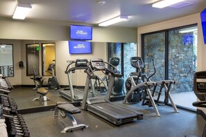 A gym with treadmills, elliptical machines, and free weights.