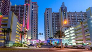 Un hotel de varios pisos con un atrio central, varios niveles de estacionamiento y palmeras.