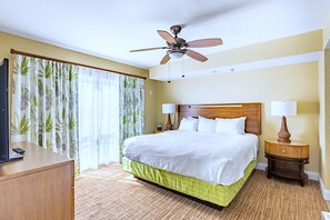 Ein Hotelzimmer mit Bett, Deckenventilator, Fernseher, Schreibtisch und Lampe.