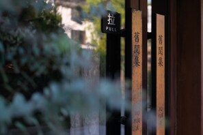 A door with a 'PULL' sign and vertical wooden panels with Chinese characters. - JiuYueJi Inn (Hangzhou)