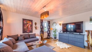 Een moderne woonkamer met een bank, televisie en decoratieve accessoires.