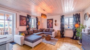 Een moderne woonkamer met een modulaire bank, een salontafel en een eethoek met een ronde tafel.