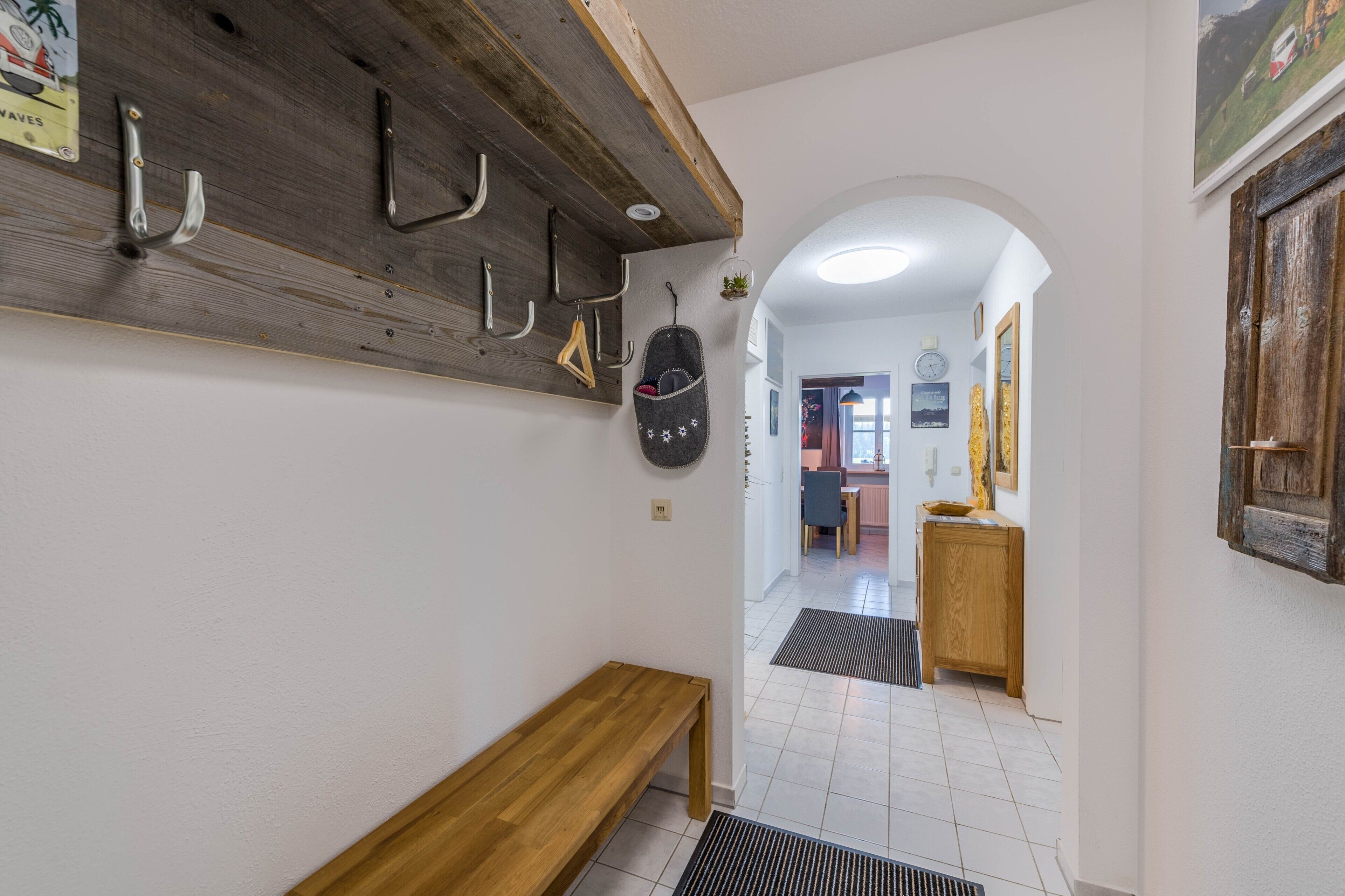 A hallway with a wooden bench, a coat rack, and a wall clock.
