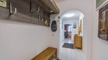 A hallway with a wooden bench, a coat rack, and a wall clock.