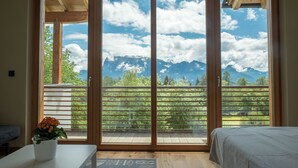 Una habitación con un amplio ventanal corredero que da a un balcón con vistas a la montaña.