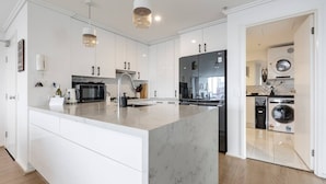 A modern kitchen with white cabinetry, a marble island, stainless steel appliances, and pendant lighting. - Melbourne and Southbank Gem with 3 bedrooms (Southbank)
