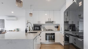 A modern kitchen with white cabinetry, stainless steel appliances, and a marble countertop. - Melbourne and Southbank Gem with 3 bedrooms (Southbank)