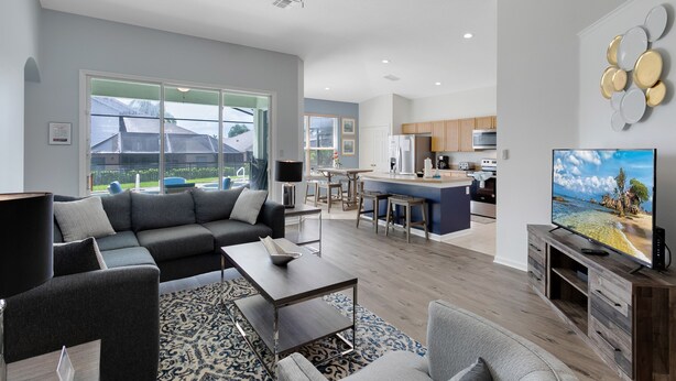 A modern living room with a sectional sofa, a coffee table, and a TV on a wooden stand.