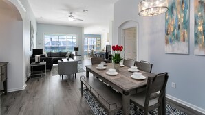 A dining area with a wooden table set for four, benches, and a chandelier.